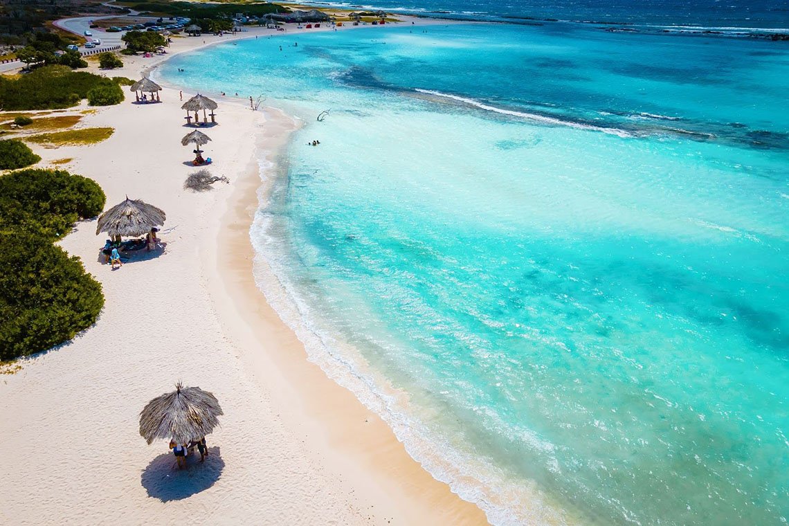 An aerial shot of Baby Beach in Aruba featuring cottages, white sand, and clear turquoise water.