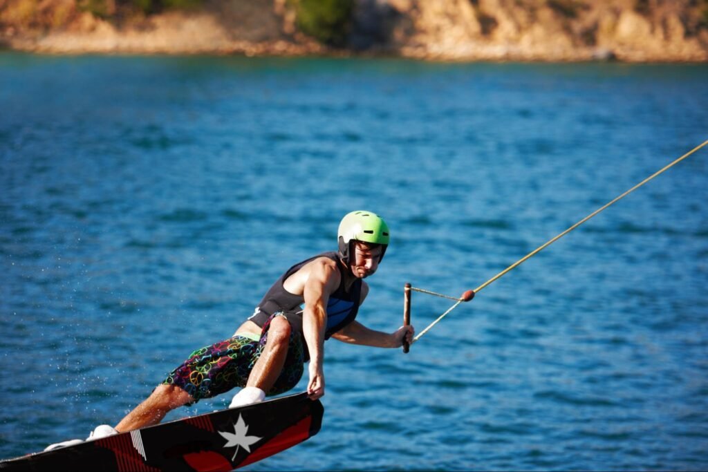 A man wearing a helmet and life jacket tries wakeboarding, a popular activity in Aruba.
