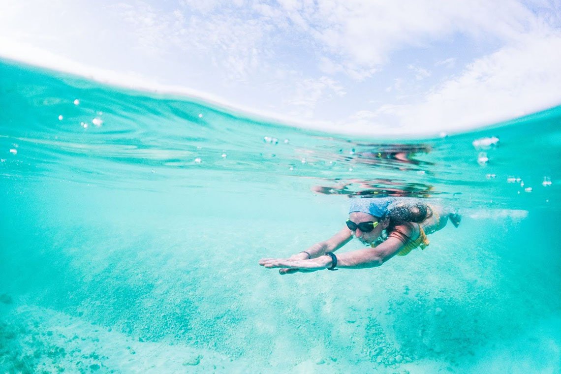 A woman snorkels underwater, showcasing one of the best things to do during excursions in Aruba.