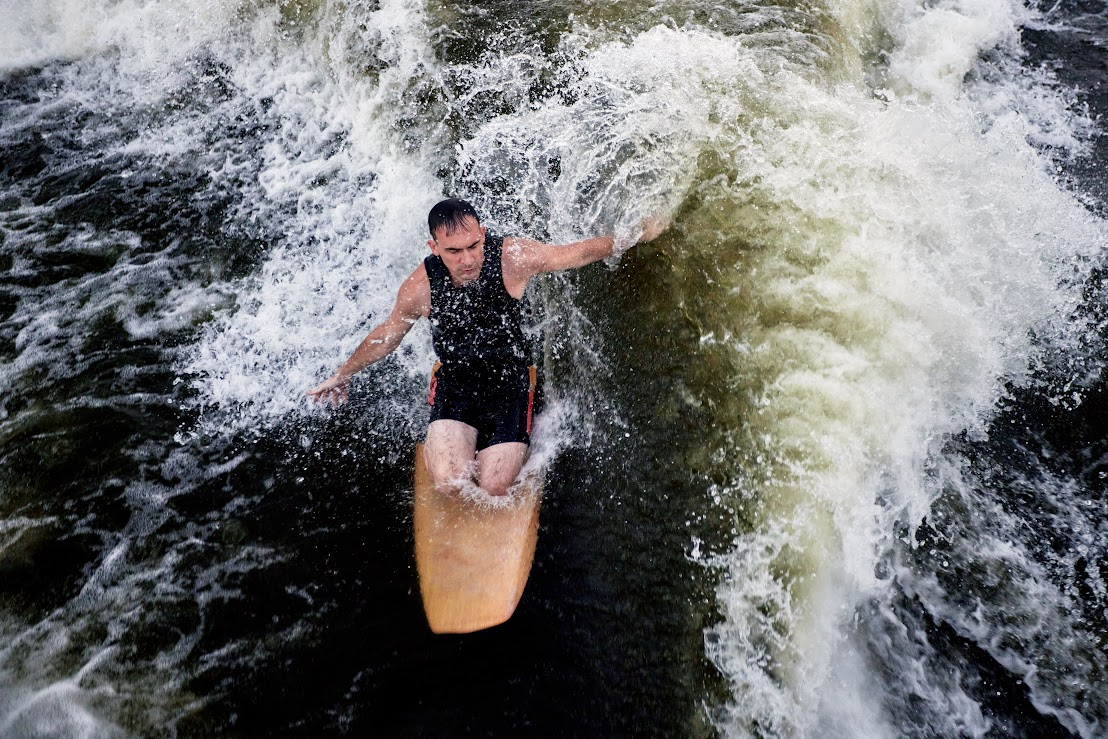 A man is on a surfboard in the water, balancing on his knees.