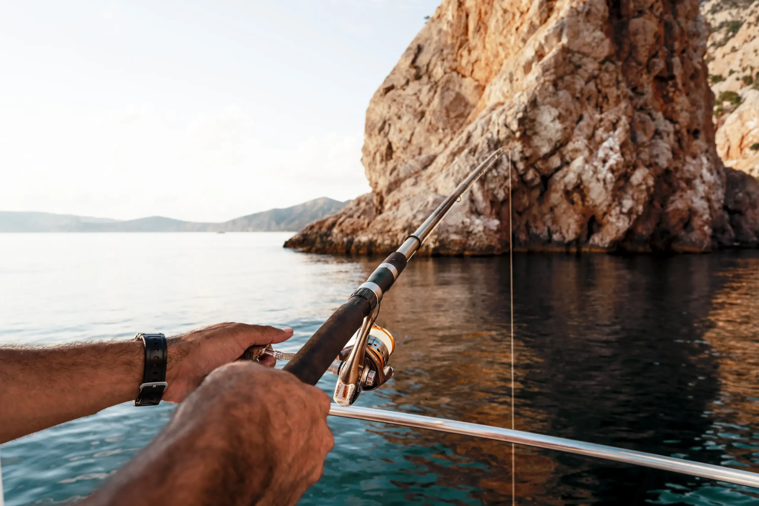 Person holding a fishing pole on the ocean