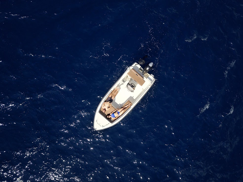 An overview of a couple lying on a boat in the water.