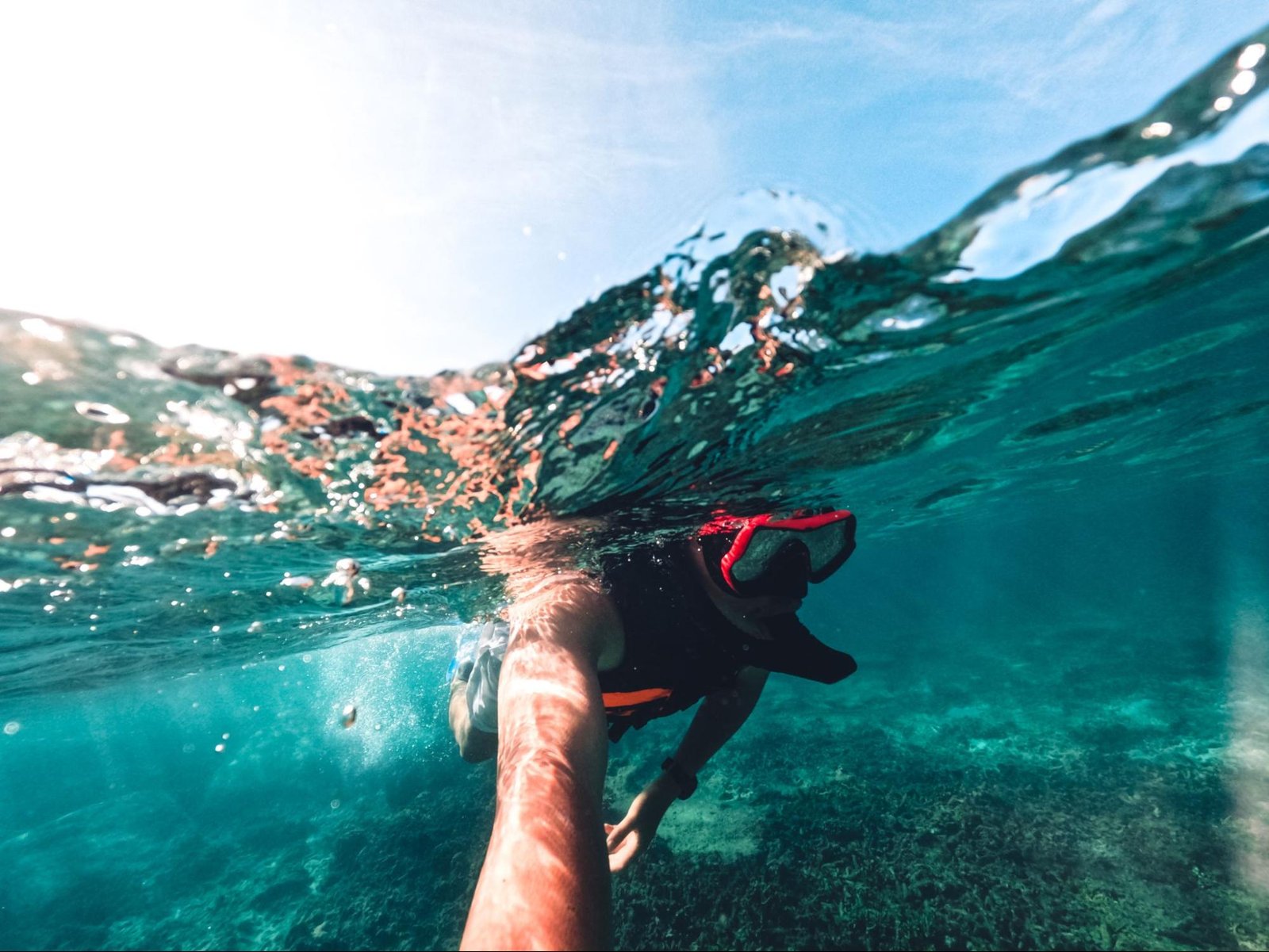 A person snorkeling under the water with an open sky.