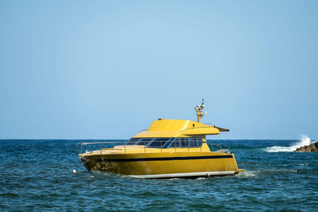 Bright yellow charter boat sailing on clear blue waters on a sunny day.