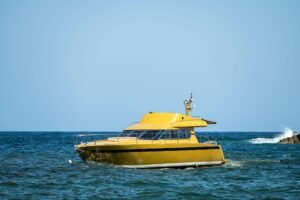 Bright yellow charter boat sailing on clear blue waters on a sunny day.